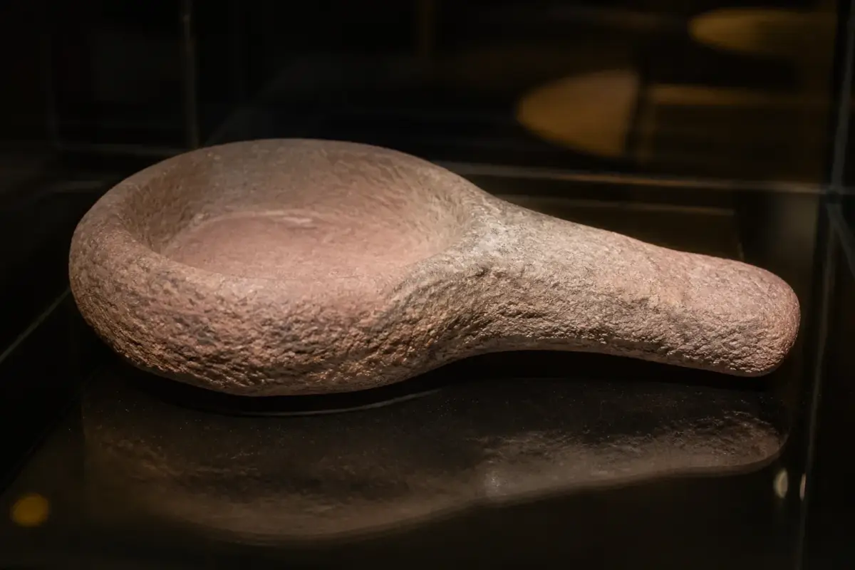 Lampe de grès rose du Magdalénien découverte dans le puits de Lascaux, exposée sous vitrine.