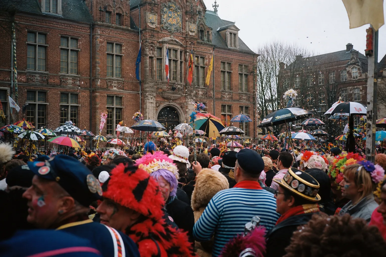 Foule de carnavaleux déguisés et parapluies colorés levés devant l'hôtel de ville de Dunkerque lors du jet de harengs.