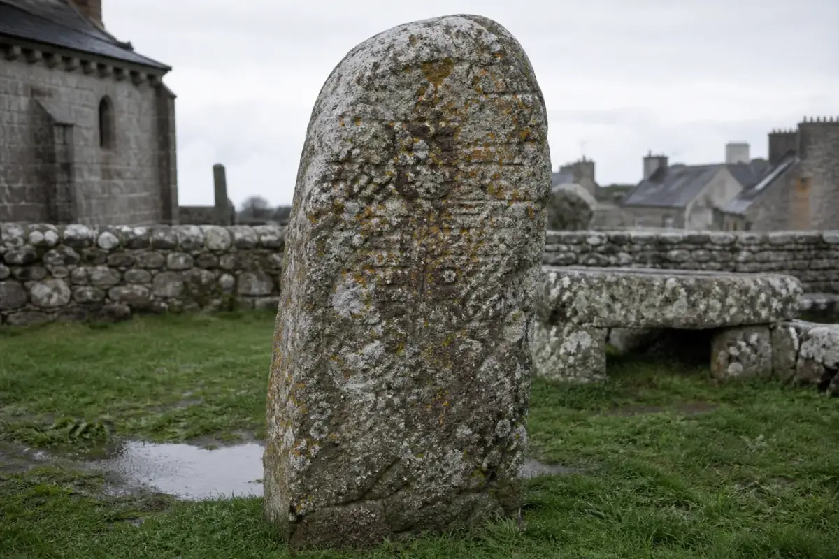 Stèle de granit couverte de lichen dressée dans l'enclos d'une église bretonne du Finistère.