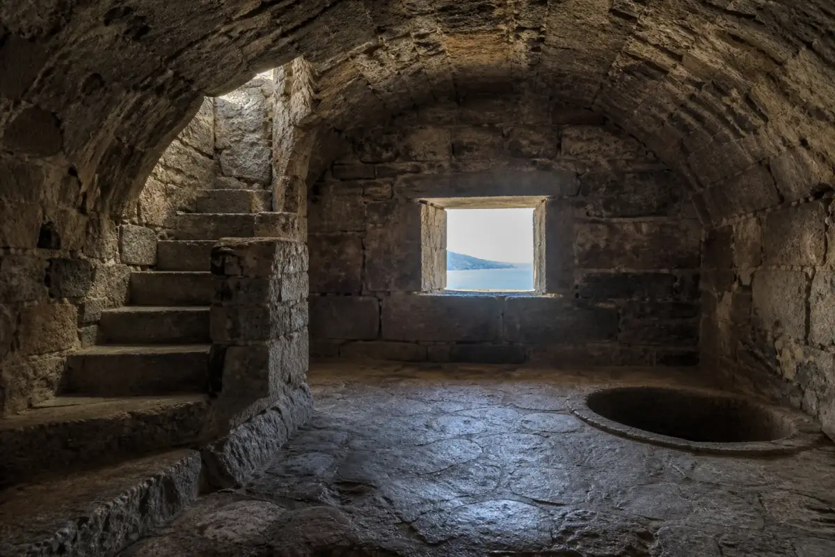 Salle de garde voûtée d'une tour génoise restaurée, éclairée par une étroite ouverture sur la mer.
