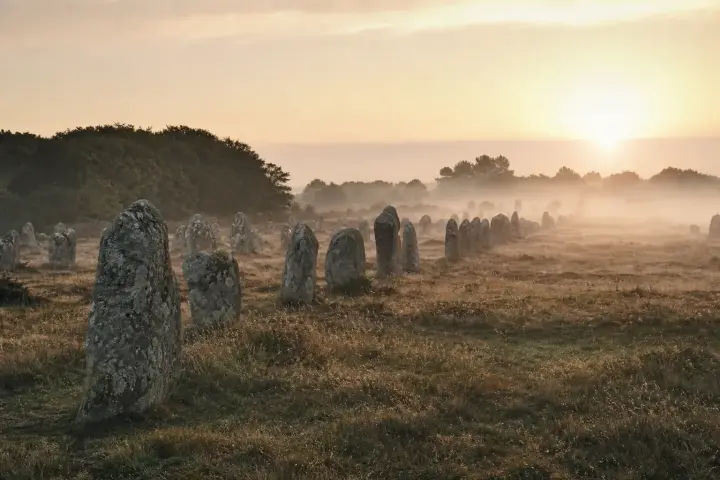 Files de menhirs de granit alignées dans la lande du Ménec à Carnac, sous un ciel breton nuageux.