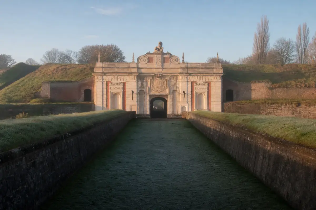 La porte Royale de la citadelle de Lille, en brique et pierre, dans son rempart de terre gazonné.