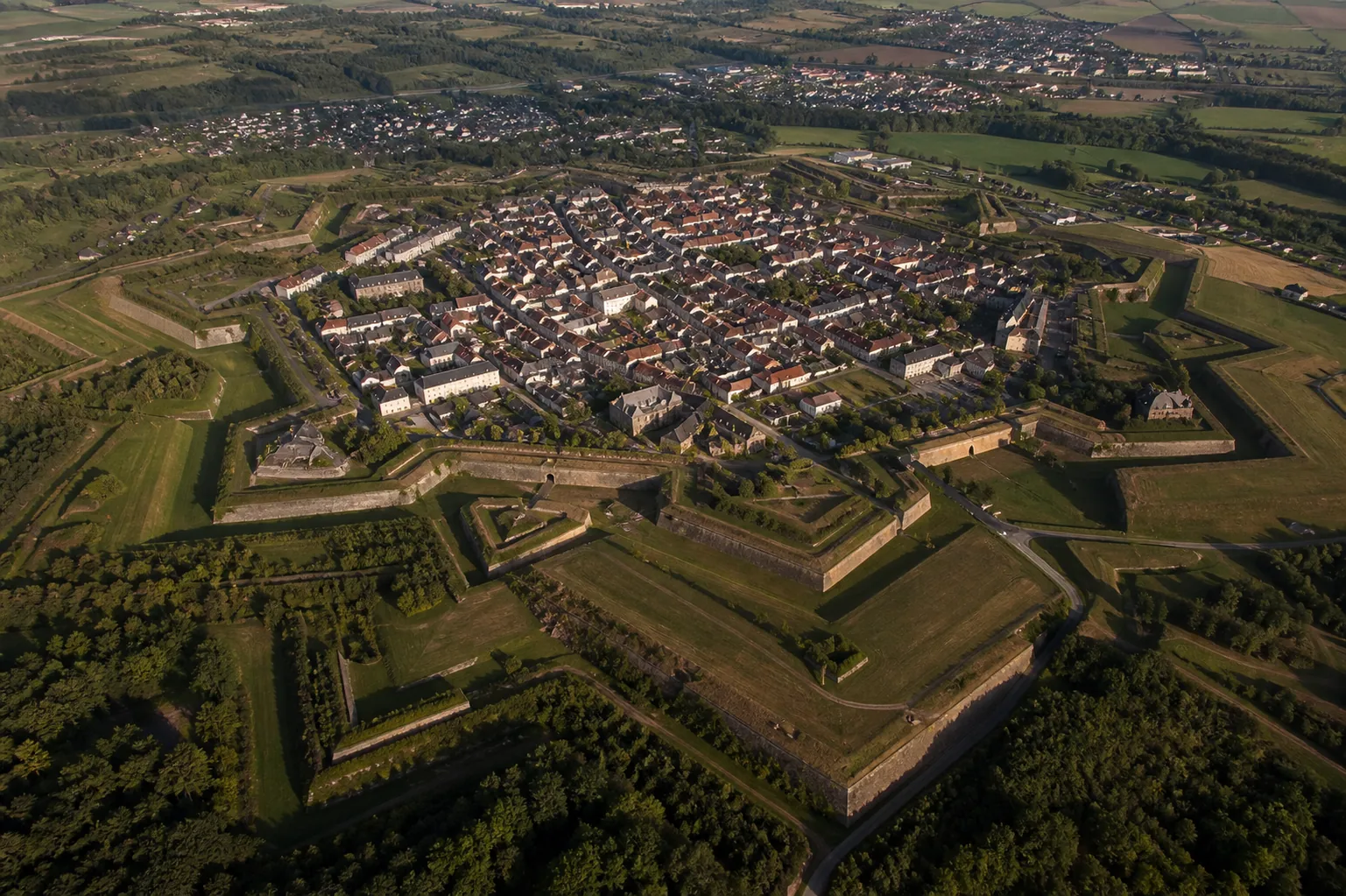 Vue aérienne des bastions en étoile d'une citadelle de Vauban entourés de fossés et de glacis herbeux.