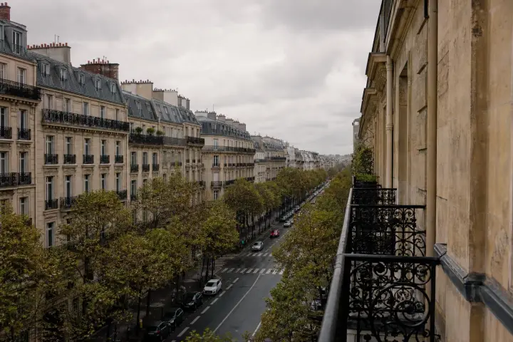 Perspective d'un boulevard parisien bordé d'immeubles haussmanniens en pierre de taille aux balcons filants.